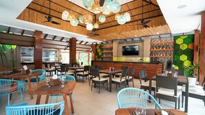 A restaurant with wooden ceiling beams, hanging lanterns, and a green hexagonal wall design.