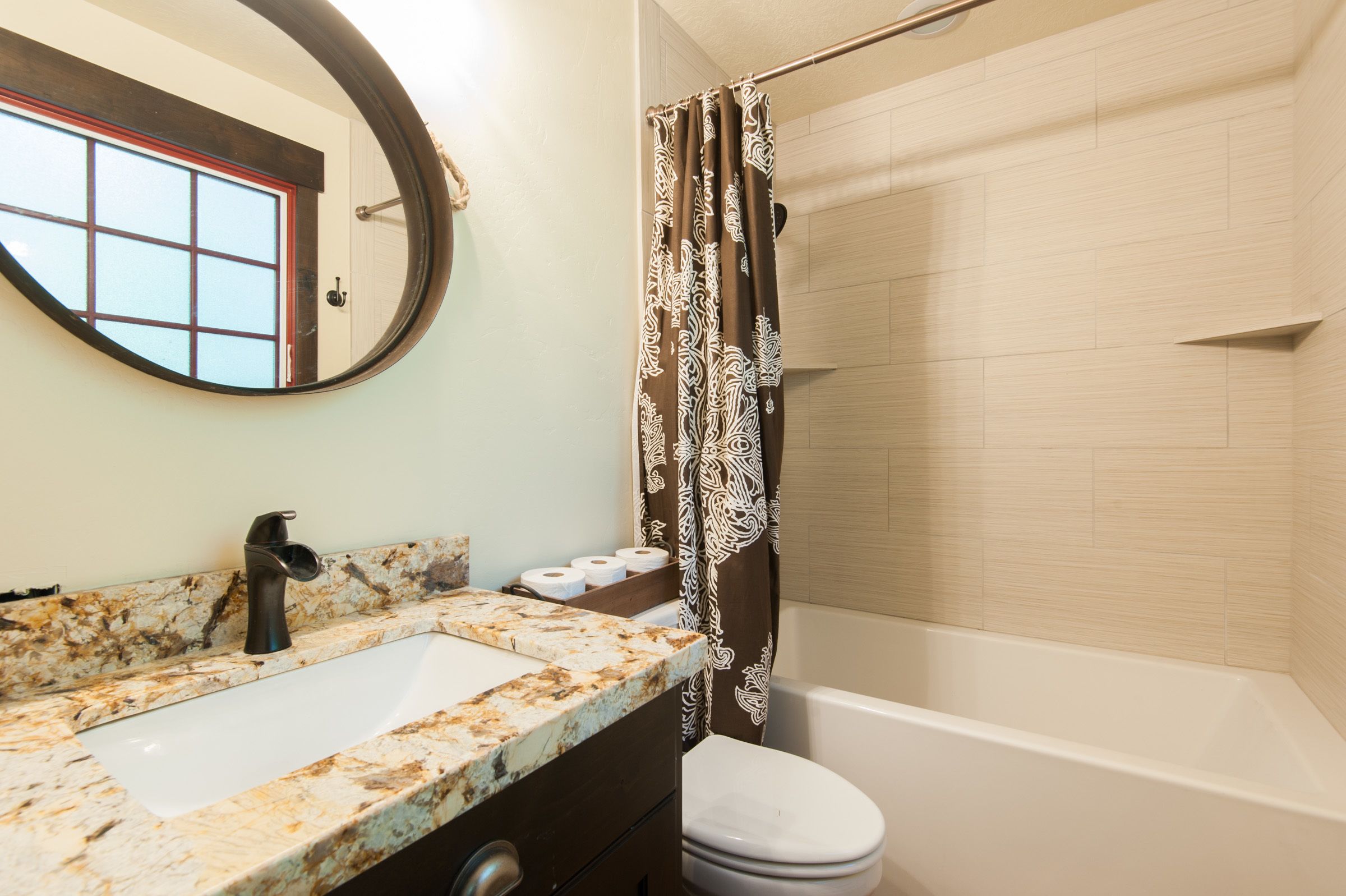 A bathroom with a marble sink, toilet, and shower area.