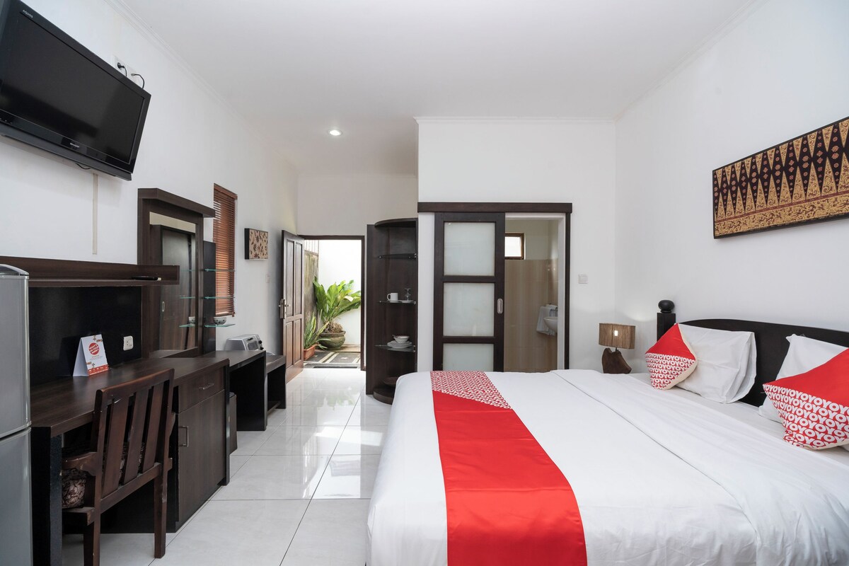 A hotel room with a bed, a desk, a television, and a door leading to a balcony.