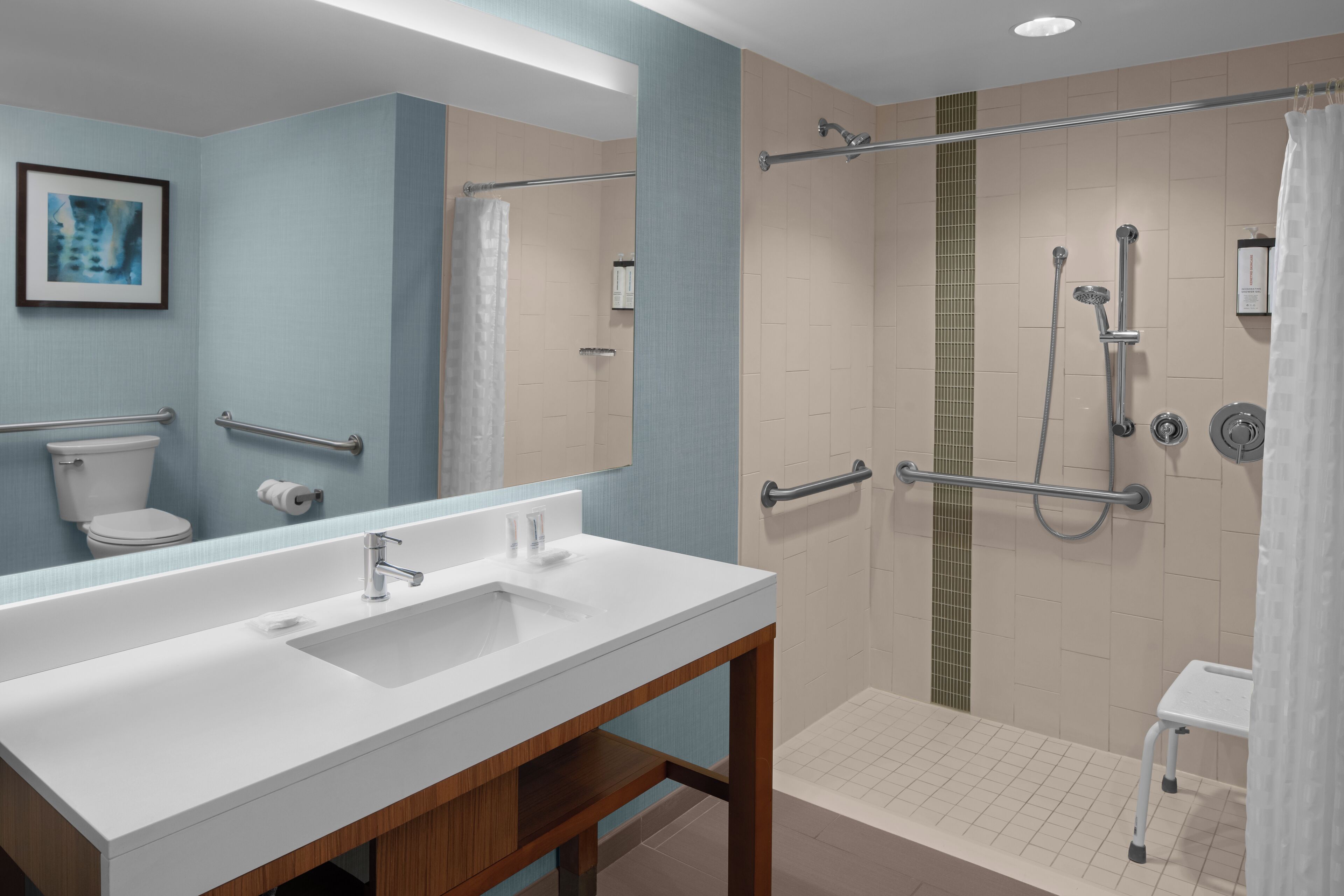 A modern bathroom with a large white sink, a mirror, a shower with a glass door, and a small white stool.