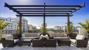 A rooftop terrace with a sectional sofa, wicker furniture, and a pergola.