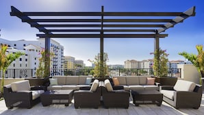 Une terrasse sur le toit avec un canapé d’angle, des meubles en osier et une pergola.