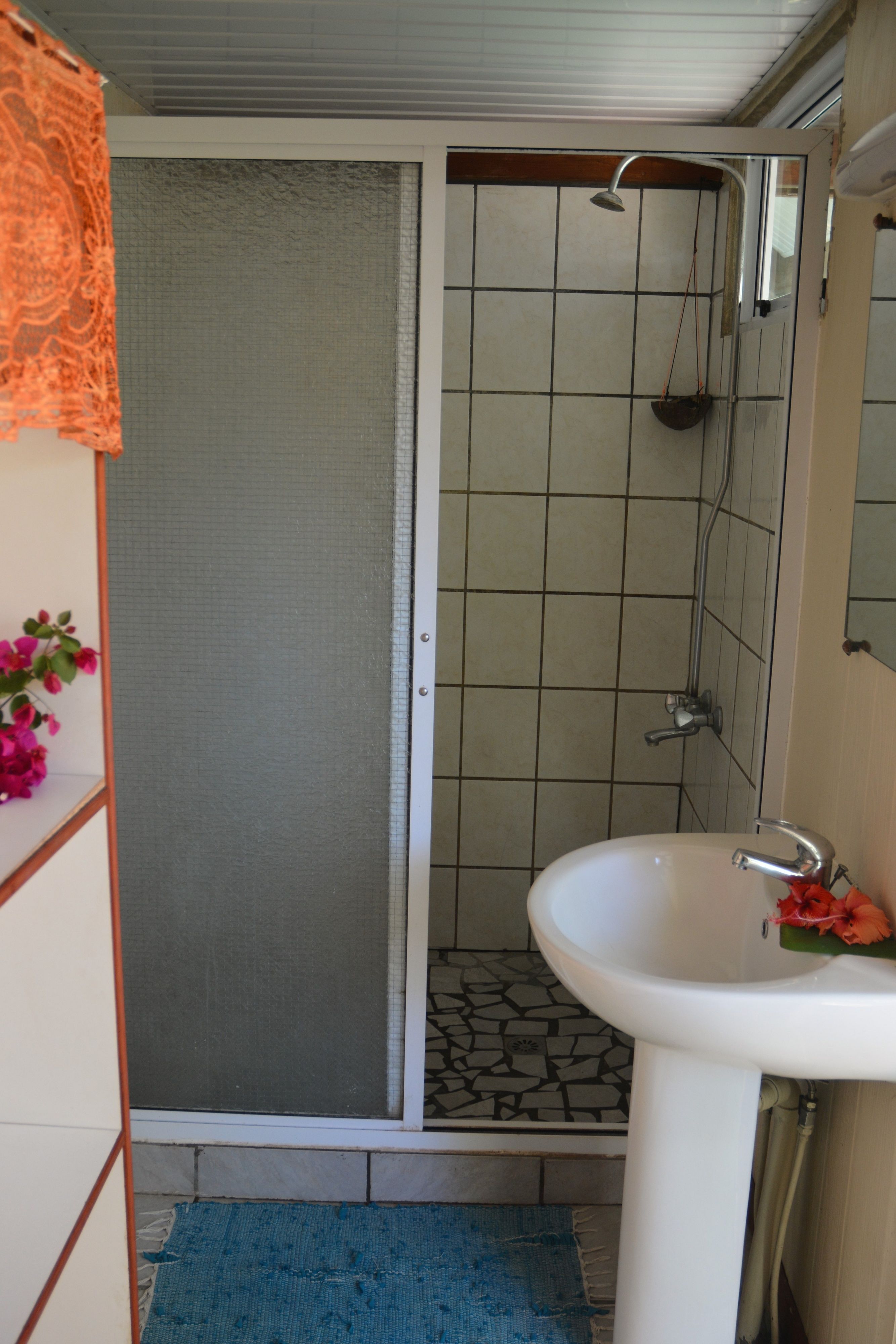 Un baño con ducha, lavamanos y suelo de baldosas.