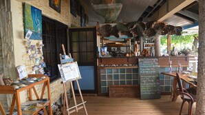 A rustic cafe with wooden floors, a wooden counter, and a chalkboard menu. - Pension Fare Maheata (Moorea-Maiao)