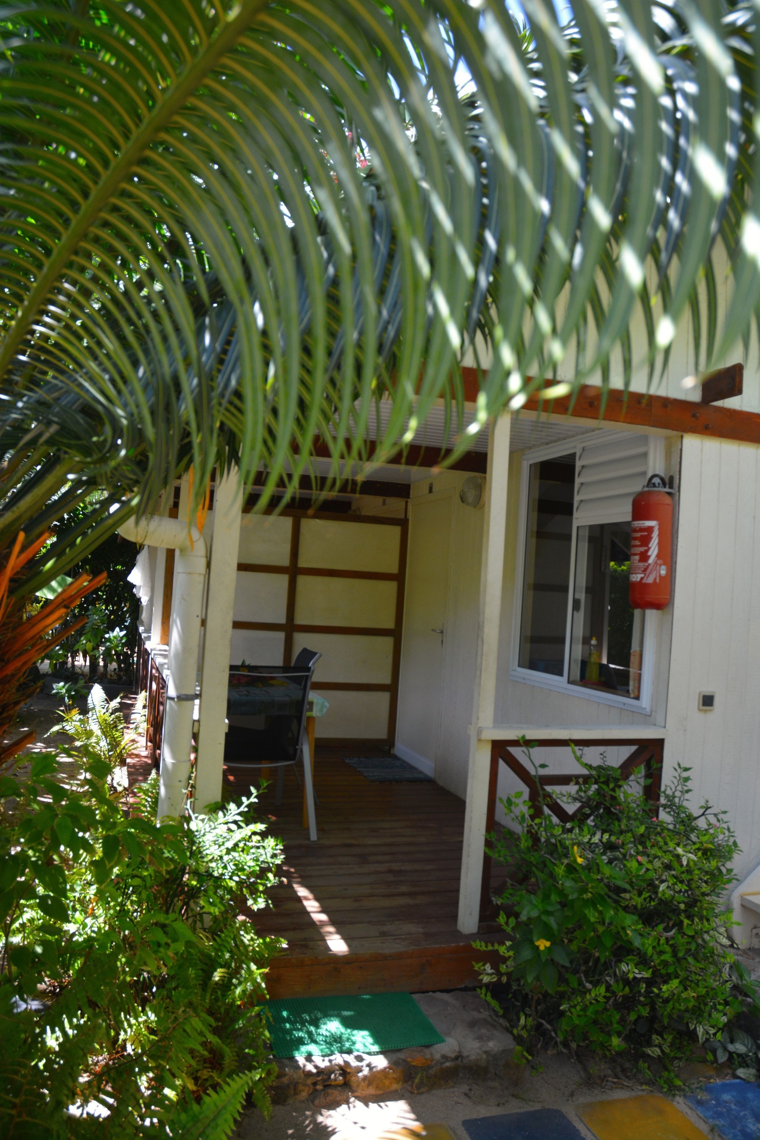 A wooden deck with a covered seating area, a fire extinguisher mounted on the wall, and a small window.