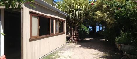 A house with a covered porch, a dirt pathway, and lush greenery.