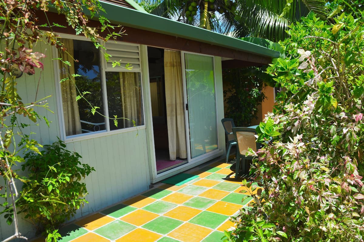 A small, single-story building with a porch area featuring a colorful tiled floor.