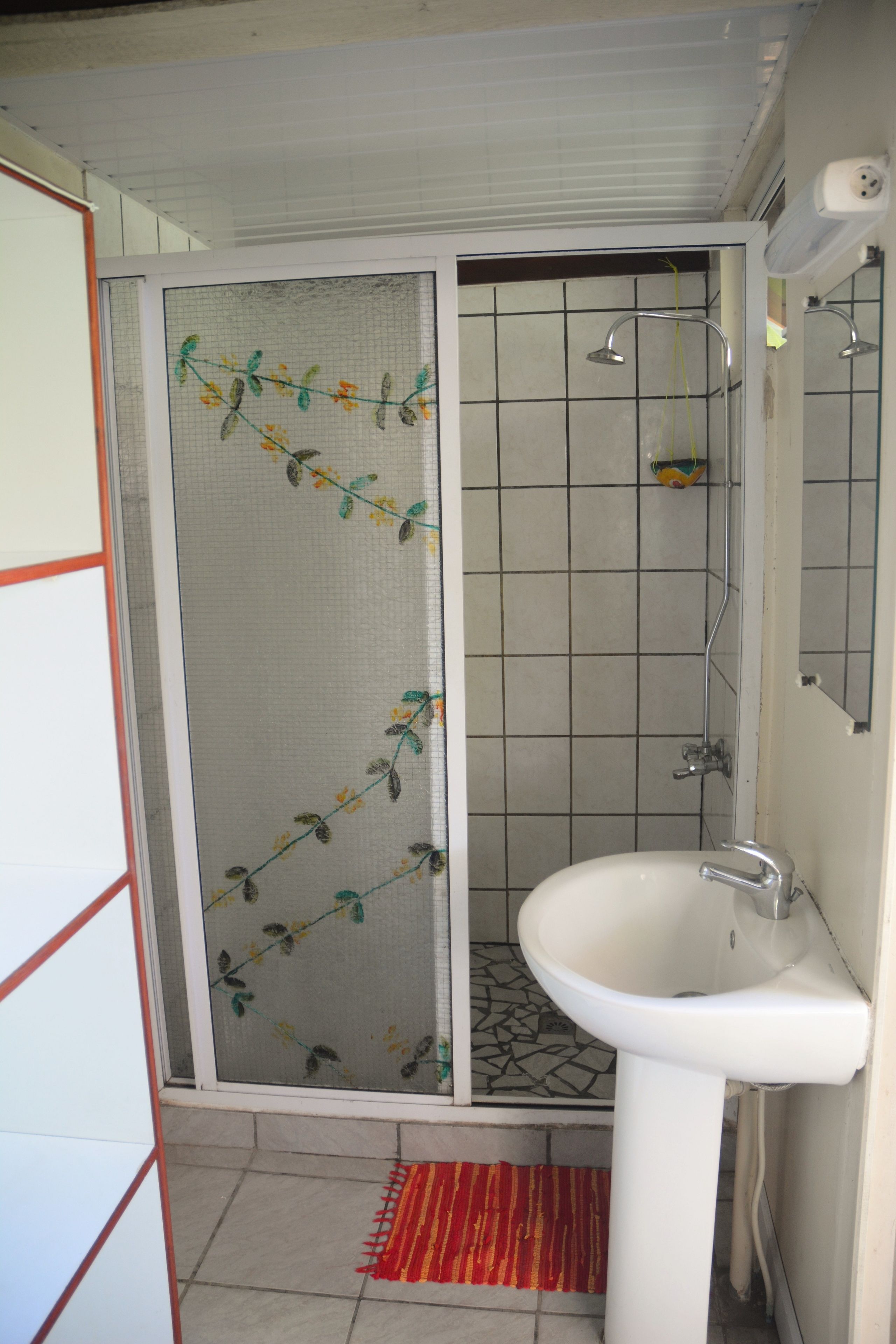 A bathroom with a shower, a sink, and a tiled floor.