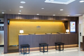 A reception desk with a flat-screen TV, two lamps, and three small tables. - Sanco Inn Nagoya Shinkansenguchi (Nagoya)