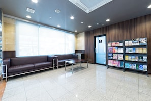 A waiting area with a brown leather sofa, a small table, and a magazine rack. - Sanco Inn Nagoya Shinkansenguchi (Nagoya)
