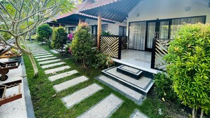 A courtyard with a tiled roof, a paved pathway, and various plants. - Mutiara Bali (Karangasem)