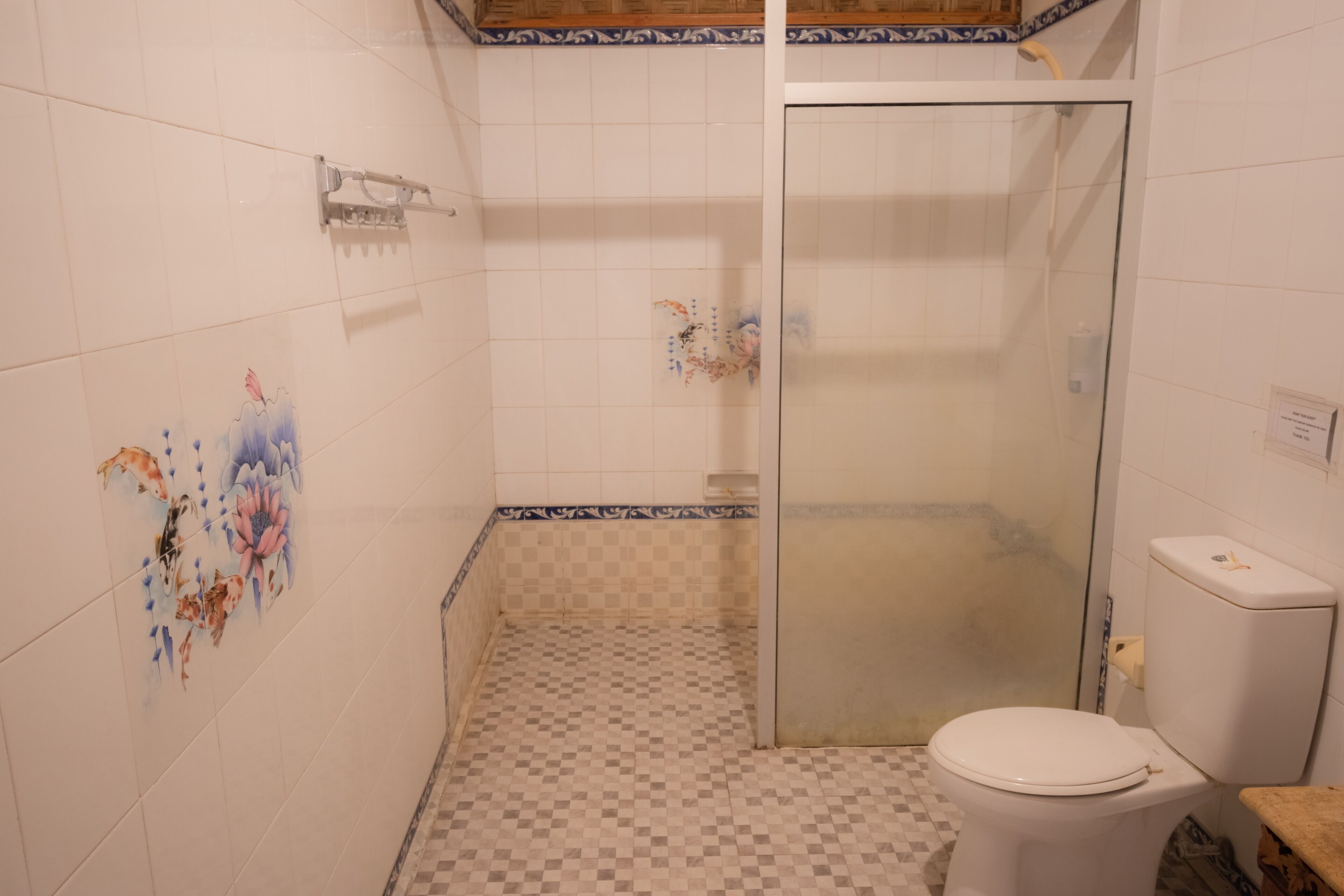 A bathroom with a toilet, shower, and decorative tiles.
