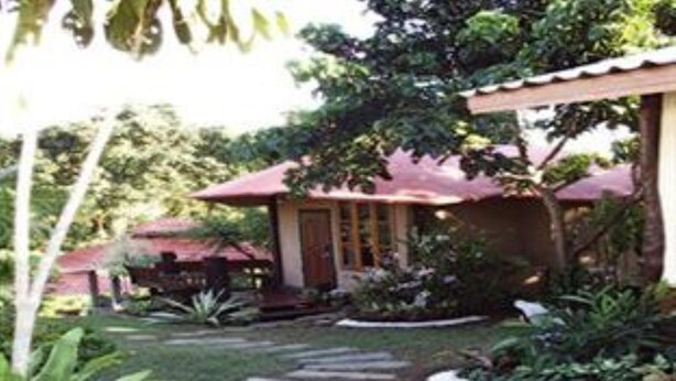 A garden with stone steps leading to a building with a red roof. - Baan Phuthadol (Mae Hong Son)