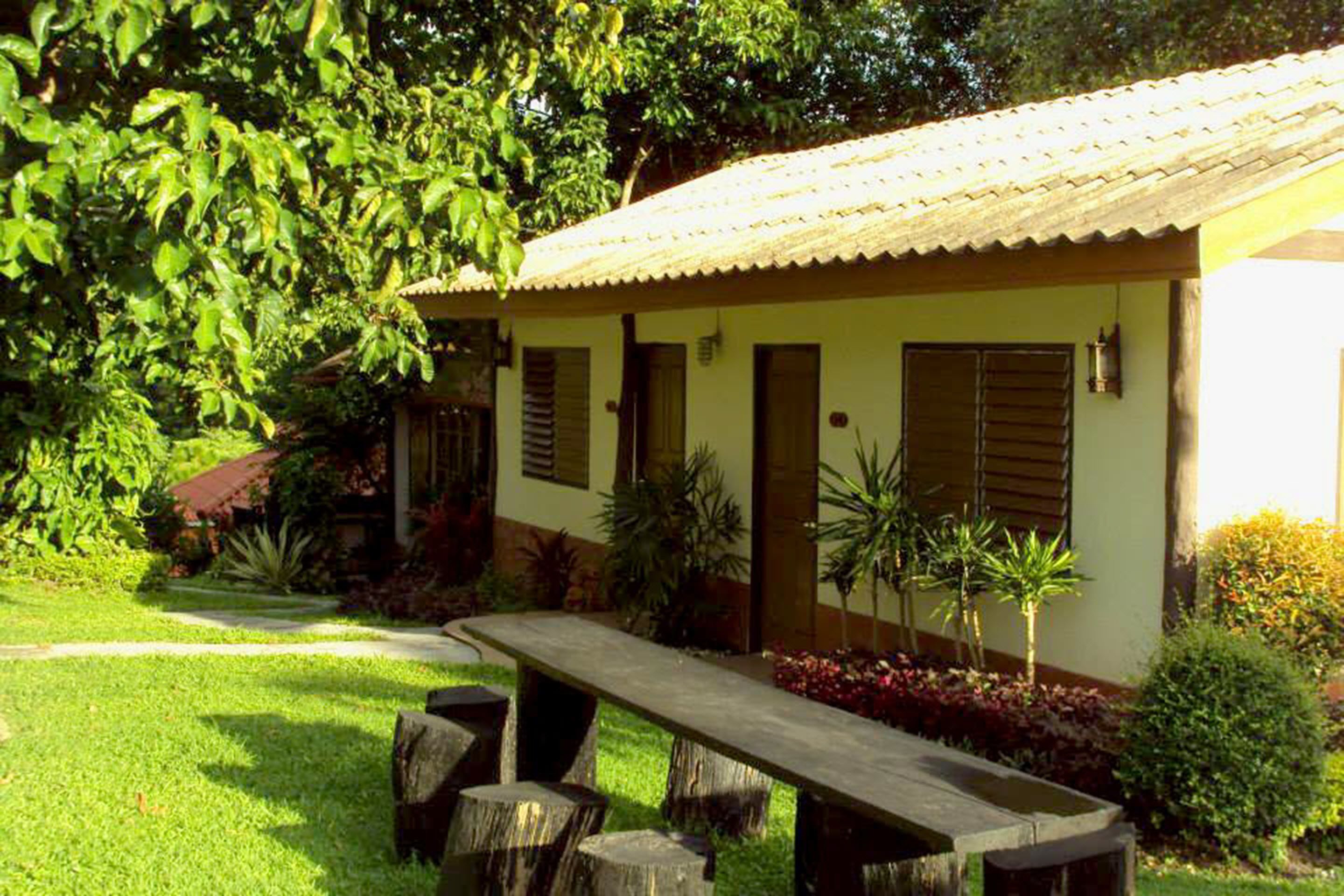 A building with a tiled roof, a front door, and a small porch area with a bench.