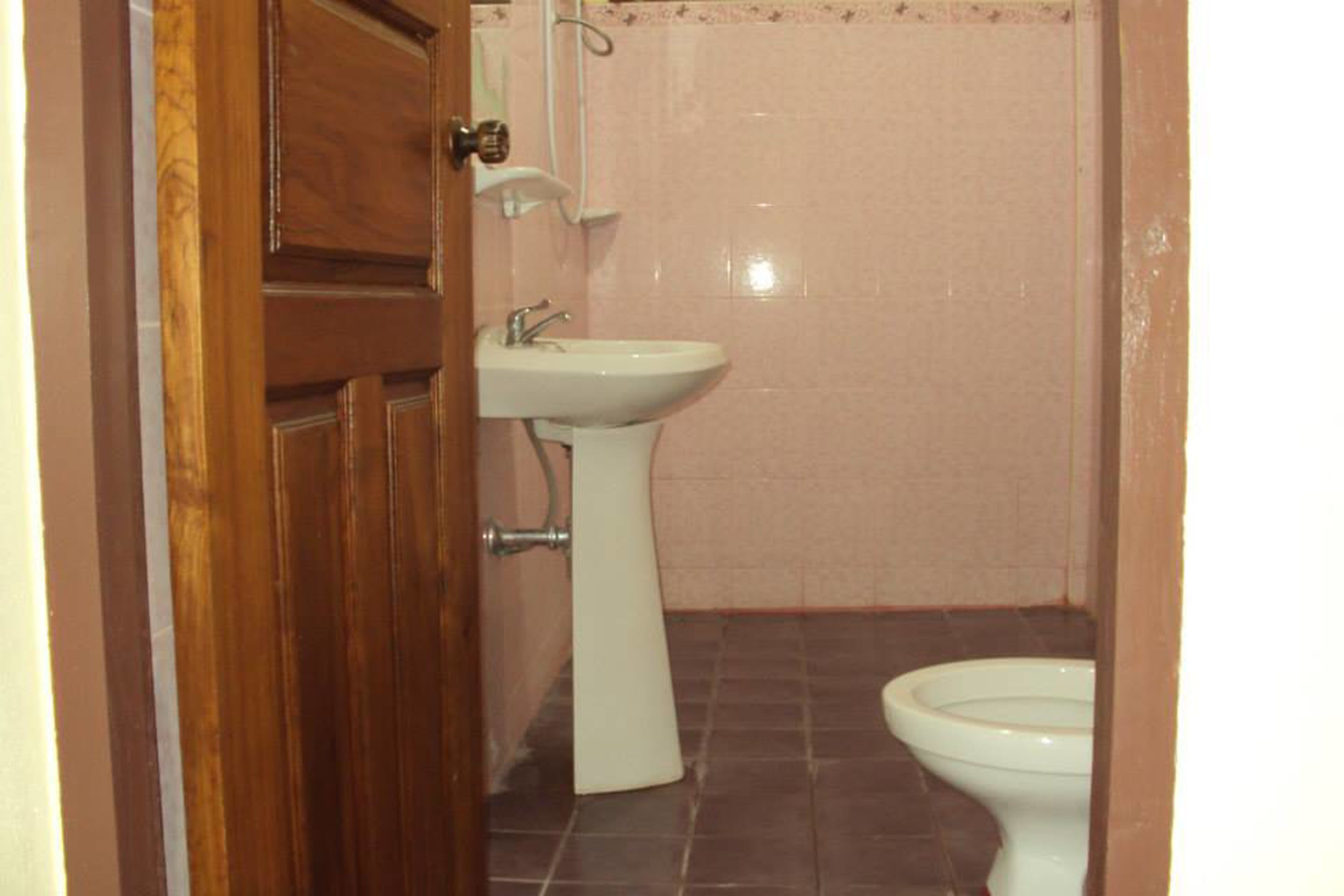 A bathroom with a wooden door, a white sink, and a toilet.