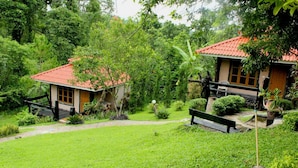 A lush garden with a pathway leading to a house with a red roof. - Baan Phuthadol (Mae Hong Son)