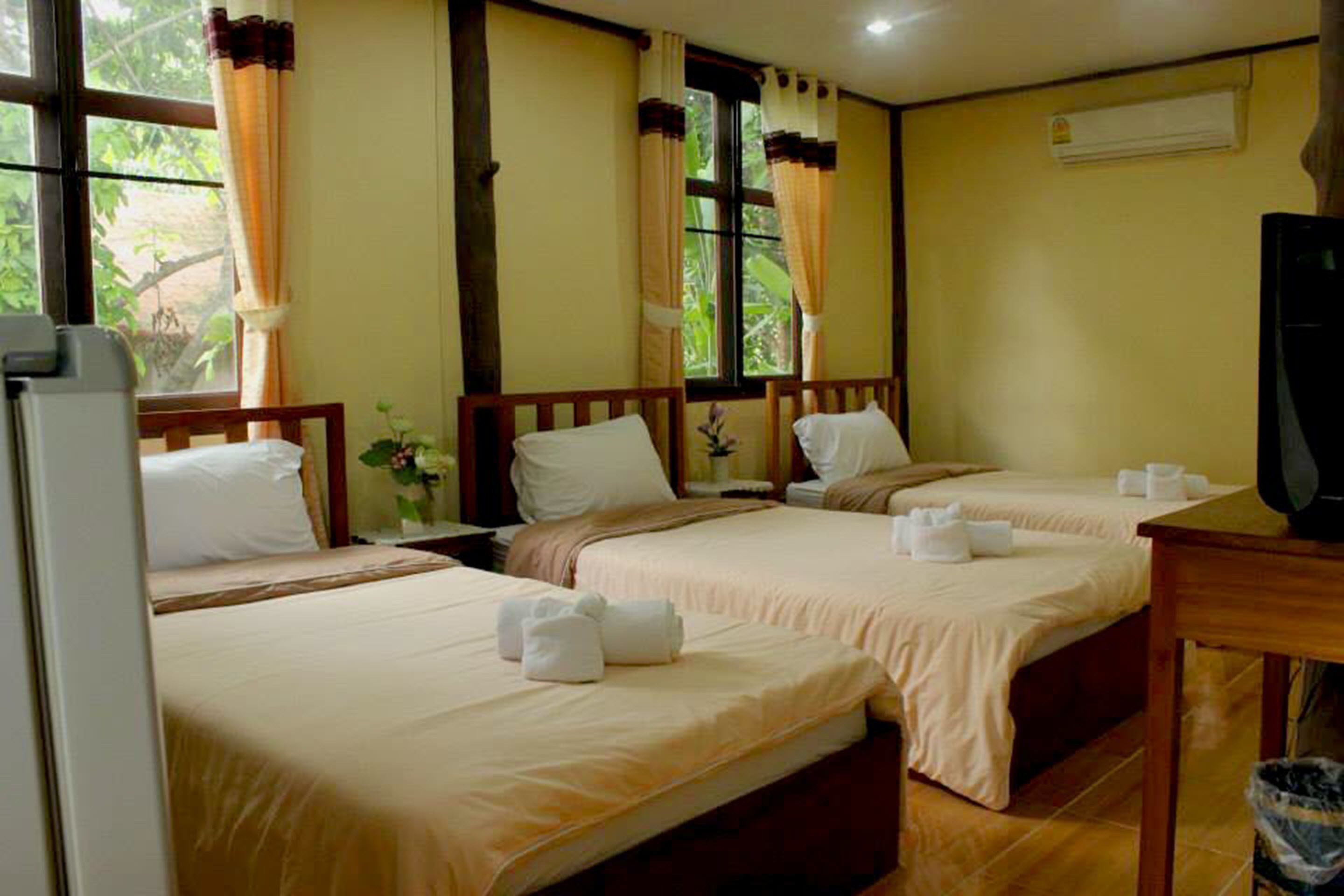 Habitación de hotel con dos camas, un televisor y una ventana con cortinas.
