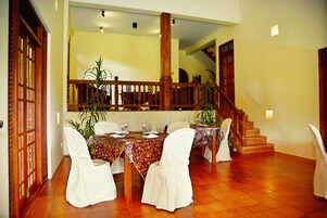 A dining area with a wooden staircase, a table set for four, and chairs with white covers.