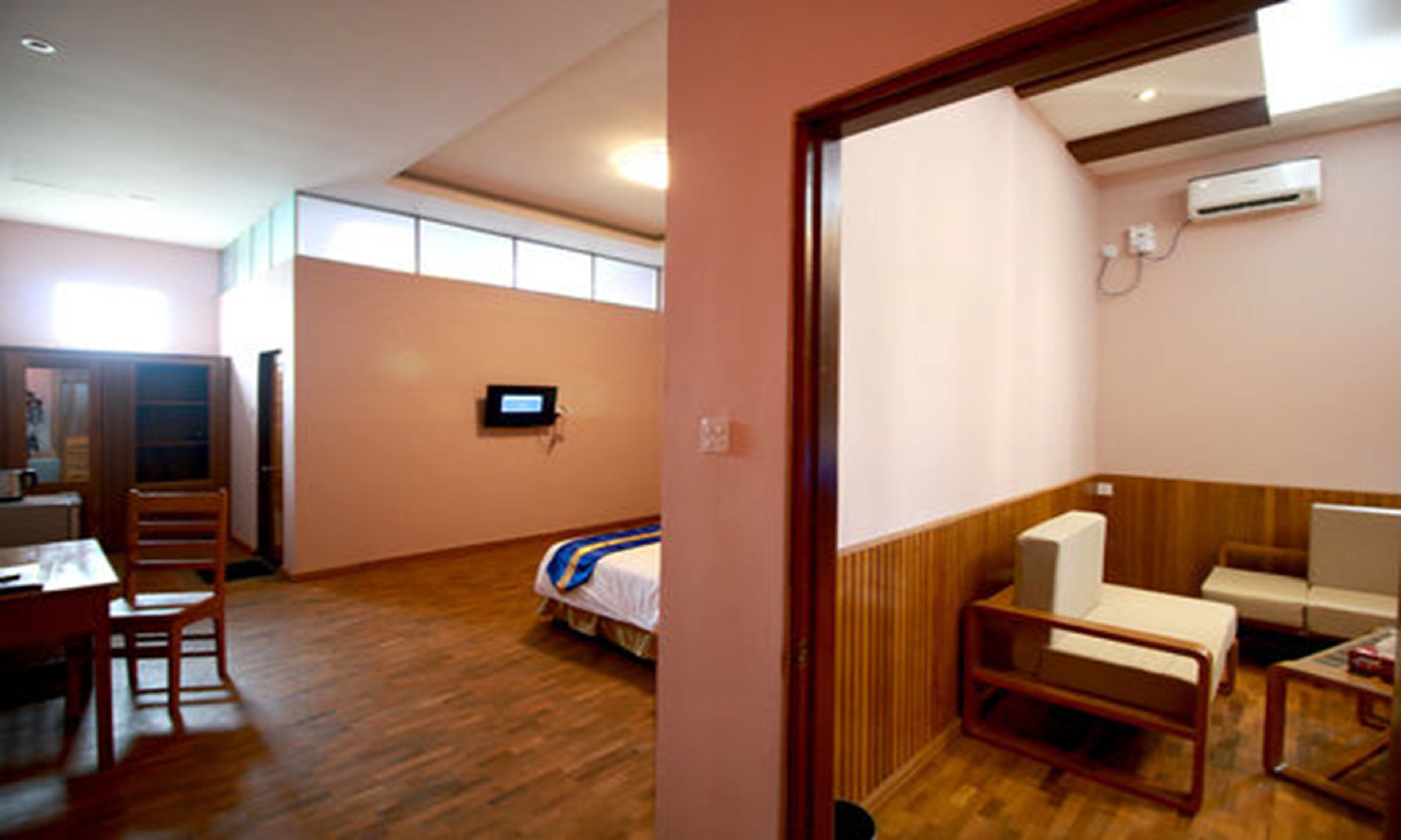 Een kleine hotelkamer met een bed, een bureau, een stoel, een televisie en een zithoekje.
