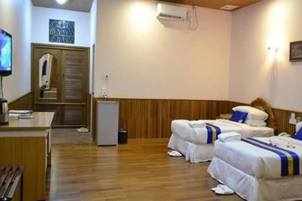 Habitación de hotel con dos camas, un escritorio, televisión y armario.
