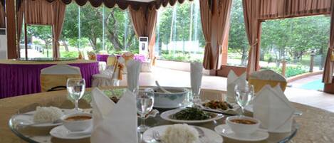 A dining table set with plates of food, glasses, and a bowl of rice.