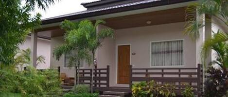 A two-story building with a wooden deck and a small porch.
