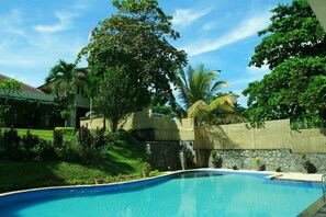Una piscina rodeada de exuberante vegetación y un muro de piedra.