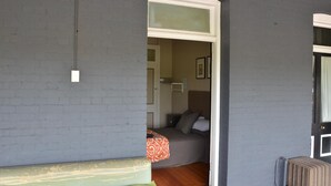 Um quarto com uma cama, um banco e uma porta que dá para outro cômodo.
