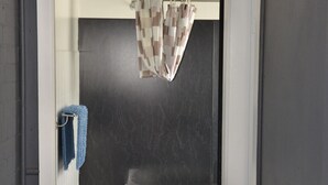 Um banheiro com piso em azulejo, pia branca e toalha pendurada em um porta-toalhas.