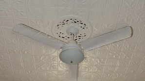 Um ventilador de teto com um centro decorativo e três pás.