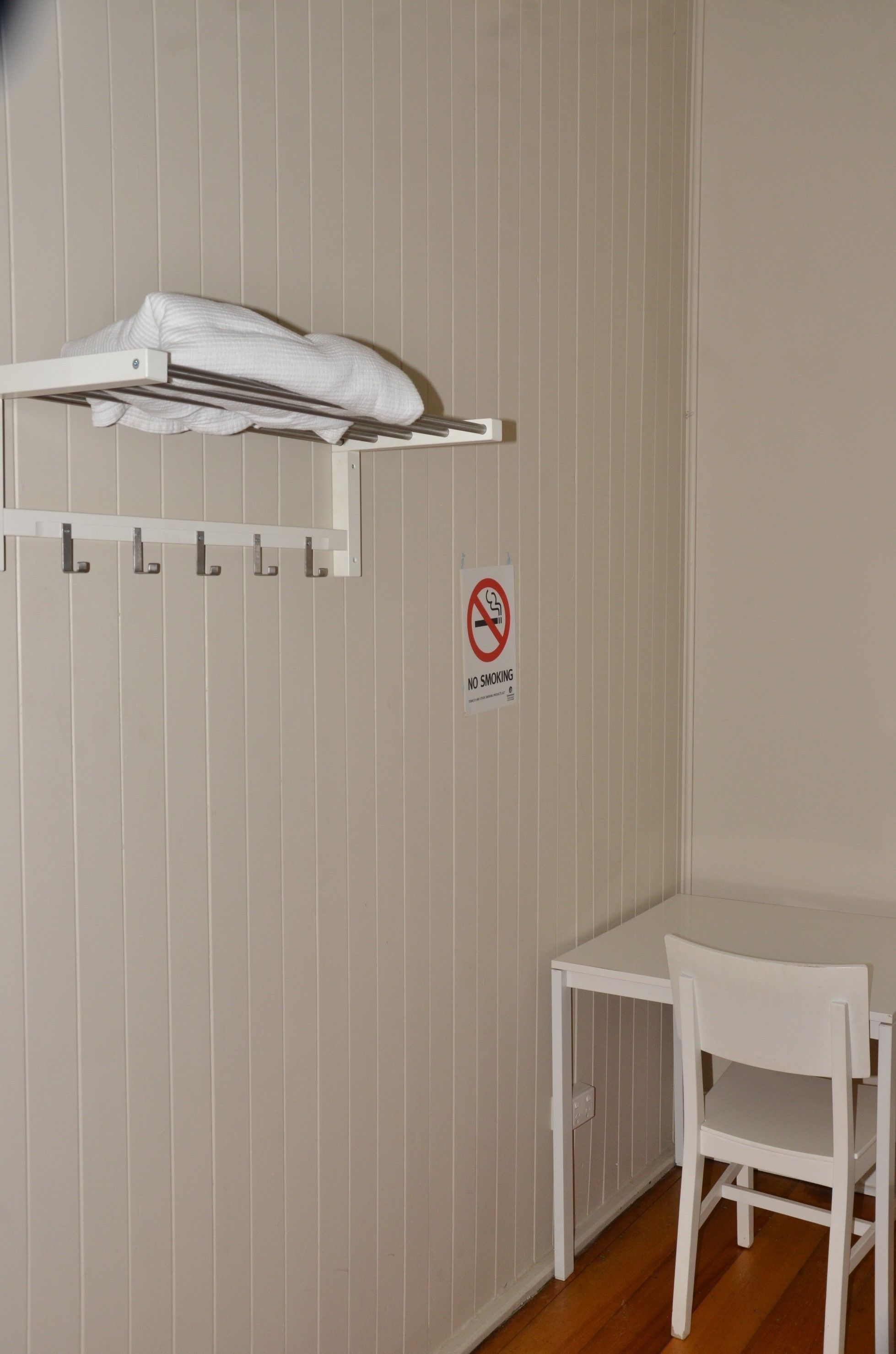 A small room with a white table and chair, a white drying rack, and a 'No Smoking' sign on the wall.