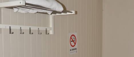 A small room with a white table and chair, a white drying rack, and a 'No Smoking' sign on the wall.