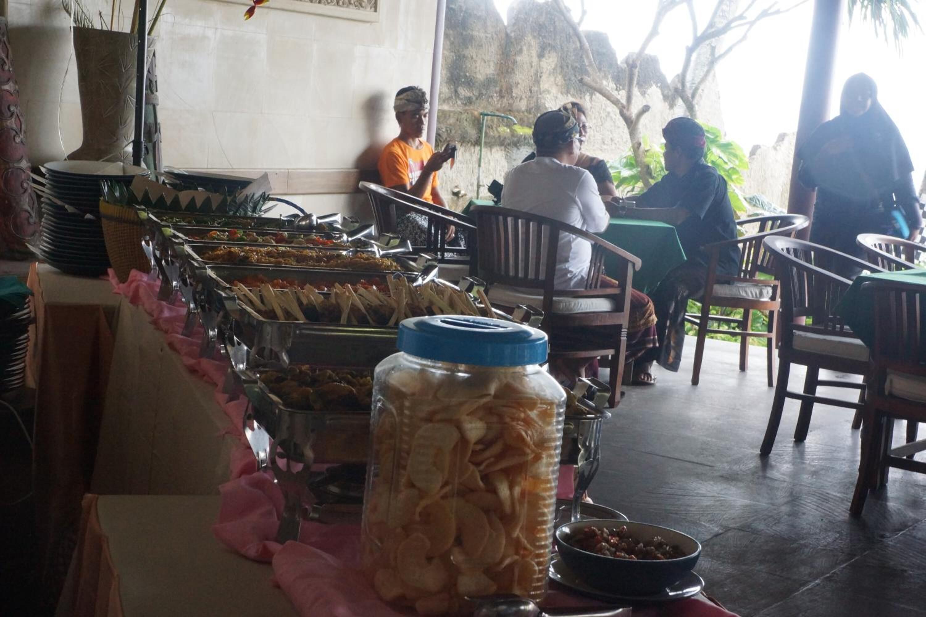 A buffet setup with various food items and a large jar of snacks.