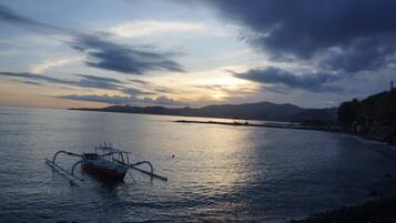A boat on calm water with a sunset in the background.