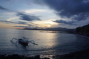 Un barco sobre aguas tranquilas con un atardecer de fondo.