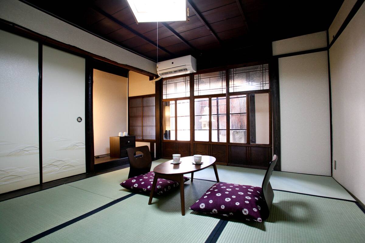 A traditional Japanese room with tatami flooring, a low table with cushions, and sliding doors.