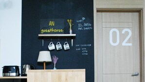 Un mostrador de recepción con una pizarra que muestra un letrero que dice "AN guesthouse" y el número "02" en la pared.