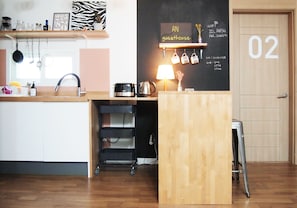 A compact kitchen with a wooden counter, a sink, and a chalkboard sign indicating a guesthouse.