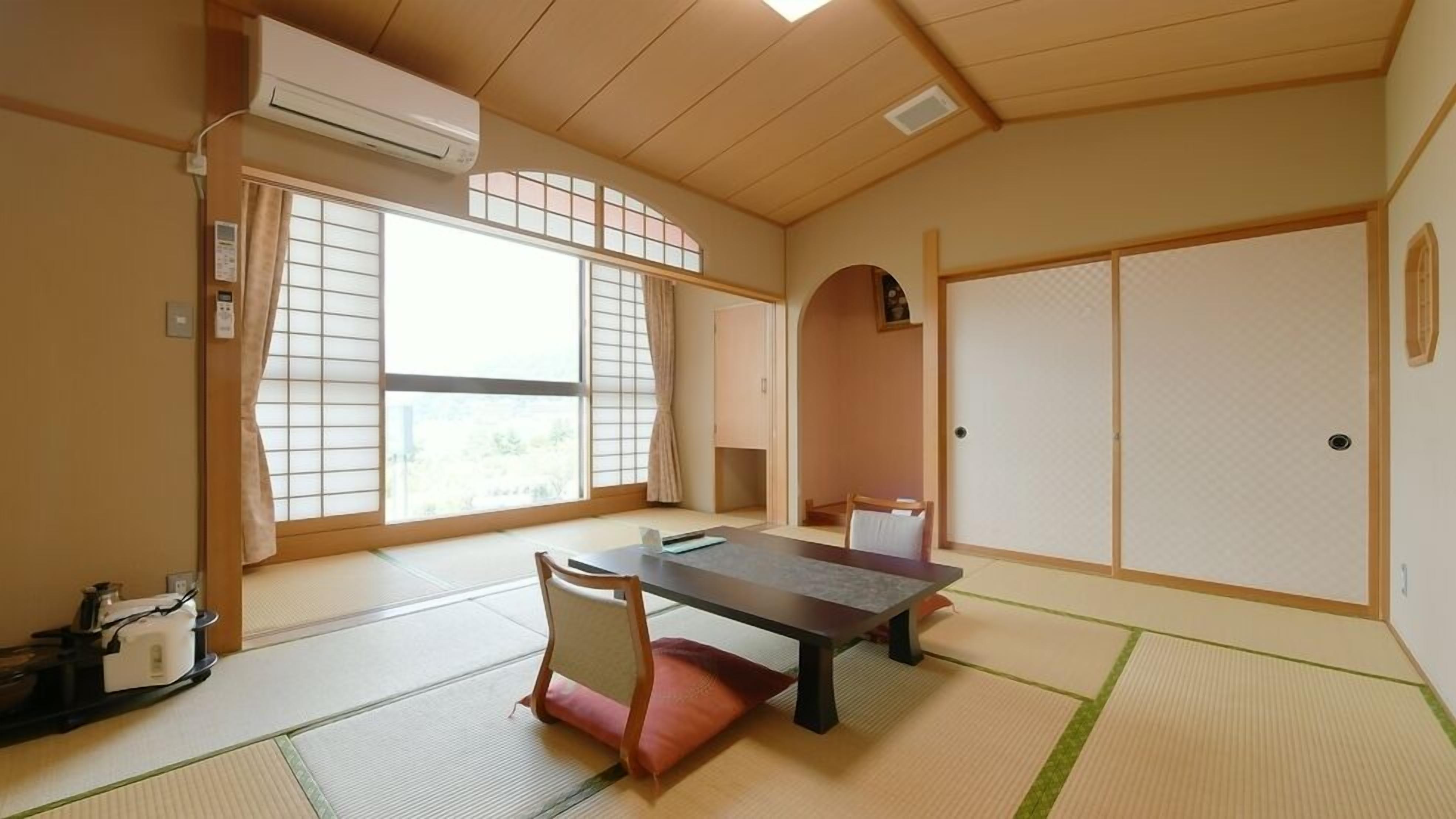 Una habitación japonesa tradicional con suelo de tatami, una mesa baja, una silla y puertas correderas.