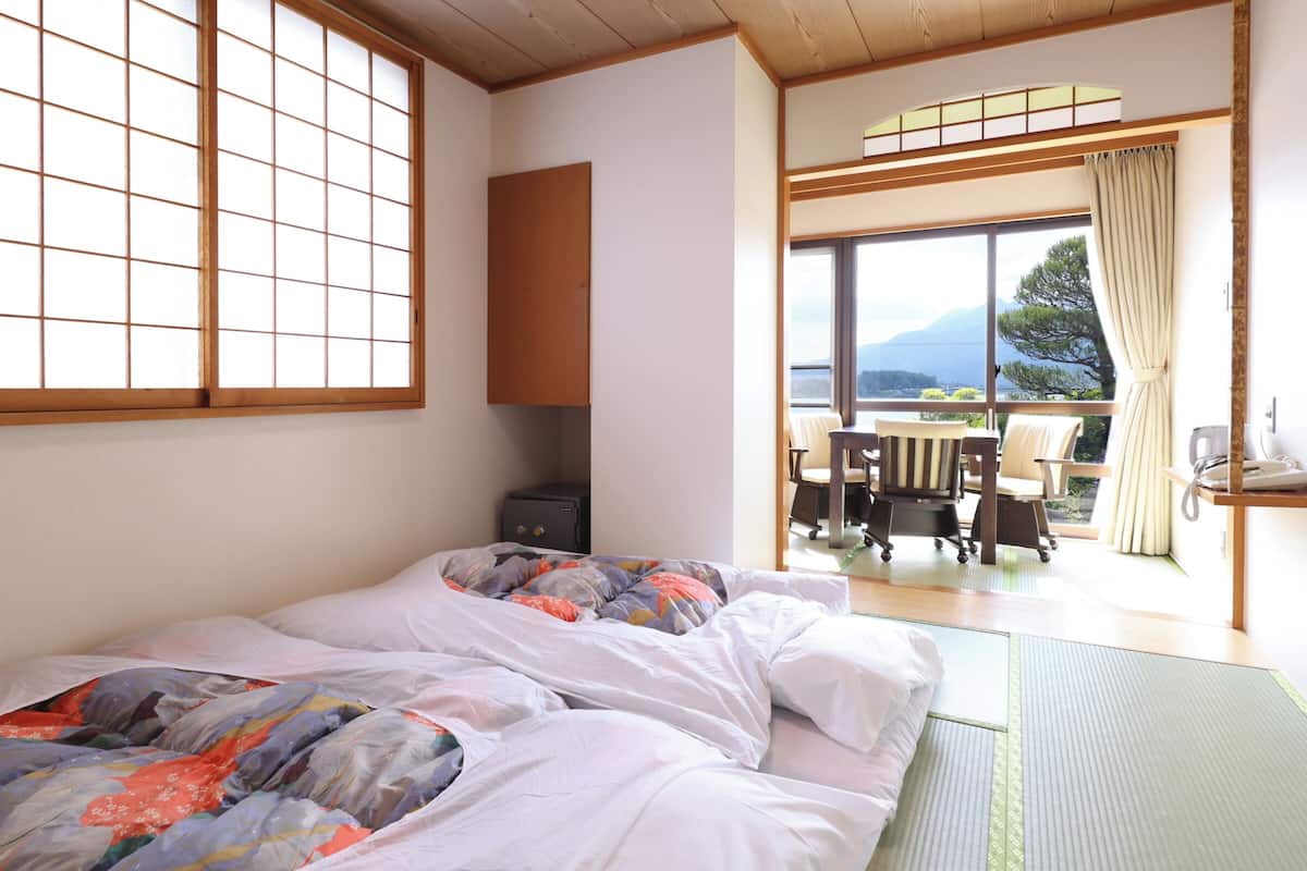 A room with a bed, a desk, and a view of the outdoors.