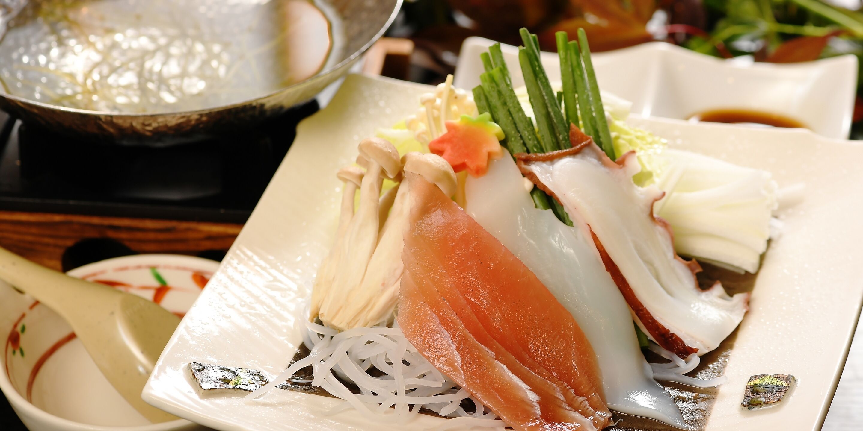 Een bord sashimi met diverse toppings, waaronder lente-uitjes en een plak zalm.