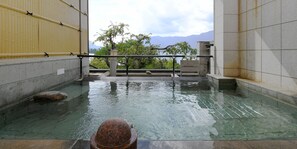 A stone-tiled pool with clear water, a rock, and a metal railing. - Hotel Koryu (Fujikawaguchiko)