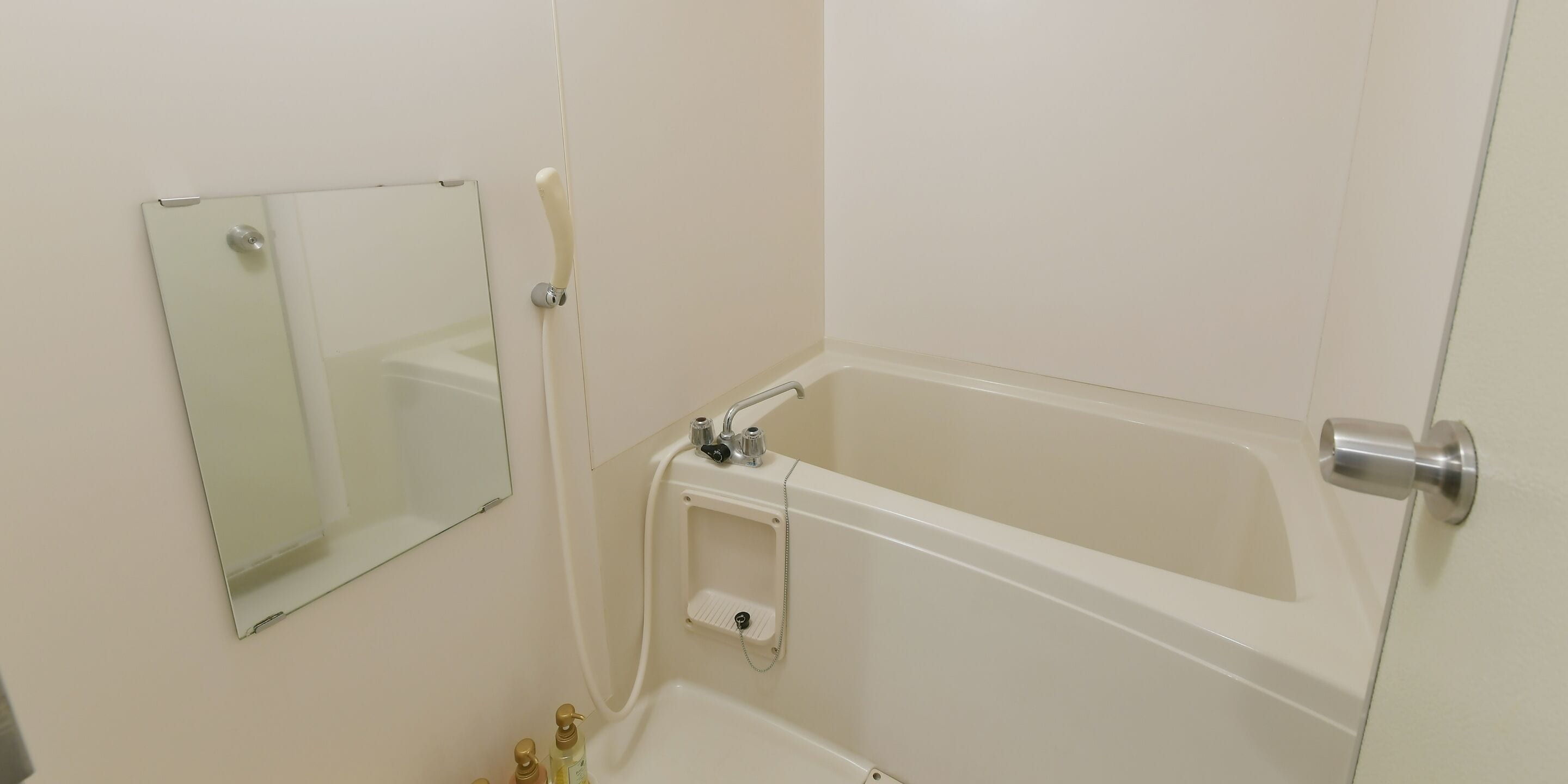 Un baño con bañera, un espejo y un estante pequeño con artículos de aseo.