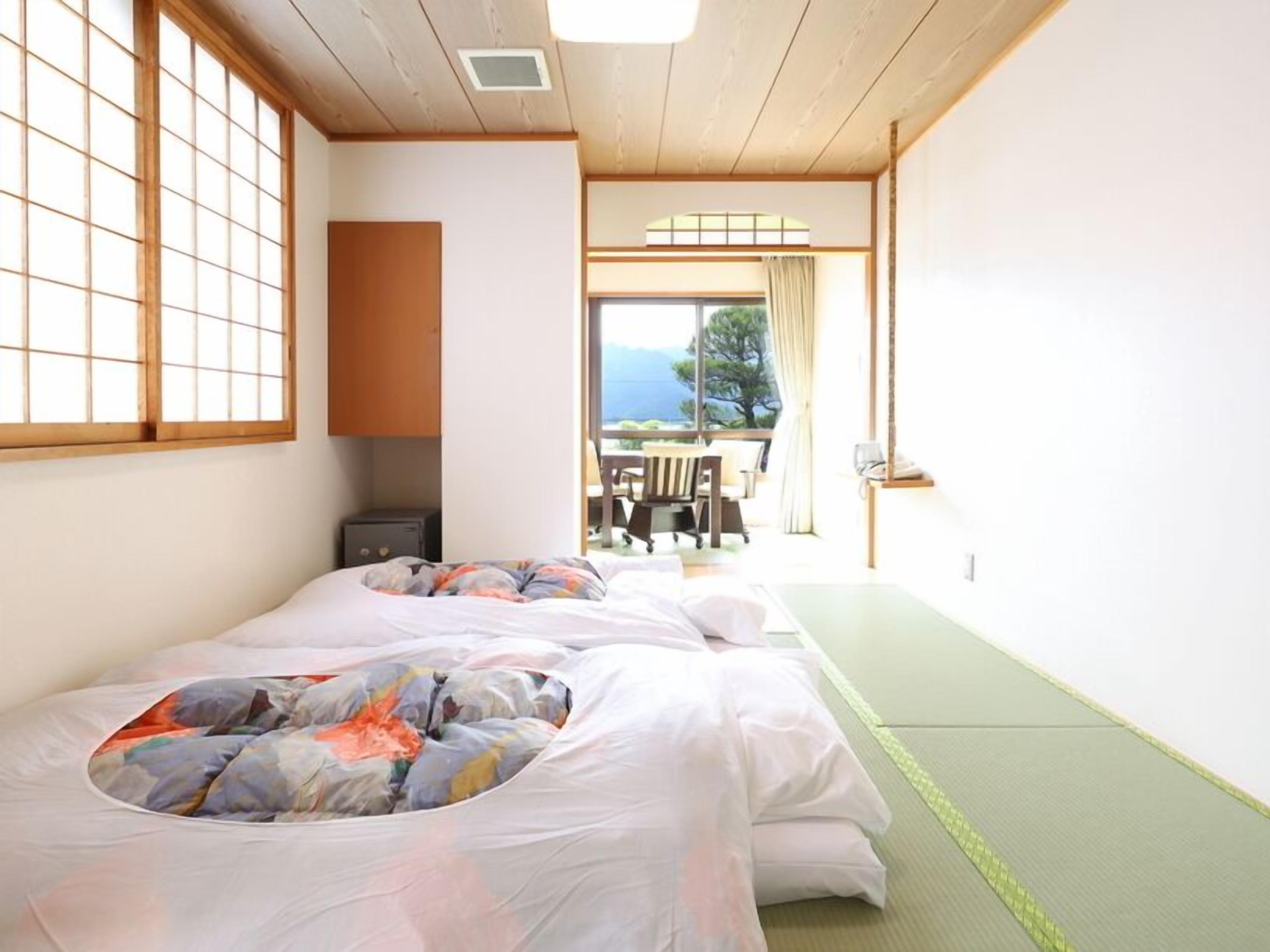 Una habitación con dos camas, una mesita y vistas al exterior.