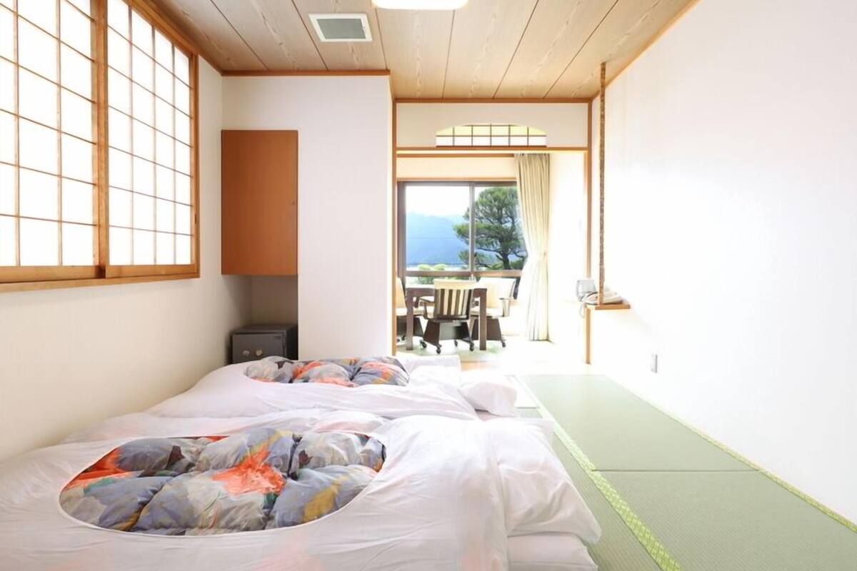 Una habitación con dos camas, una mesita y vistas al exterior.