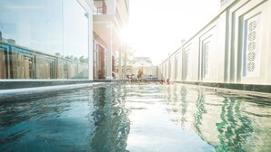 A swimming pool with clear water, surrounded by buildings with large windows and balconies.