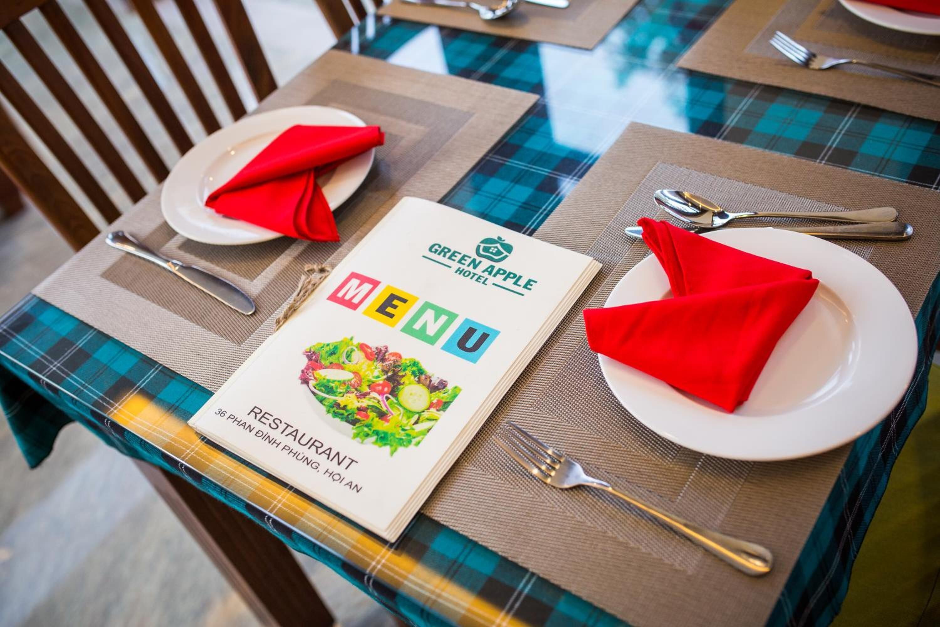 A table set with a menu, red napkins, and silverware.