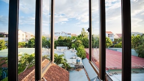 Vista desde un edificio de gran altura con amplias ventanas, que muestra un paisaje urbano con diversos edificios y zonas verdes.