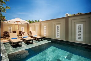 Een buitenzwembad, parasols bij het zwembad en ligstoelen