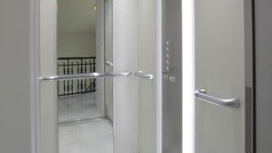 A modern elevator with a glass door, a digital display, and a handrail. - Hotel Rosal (Oviedo)
